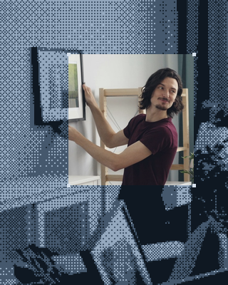 A man hangs a frame on the wall of his new place.