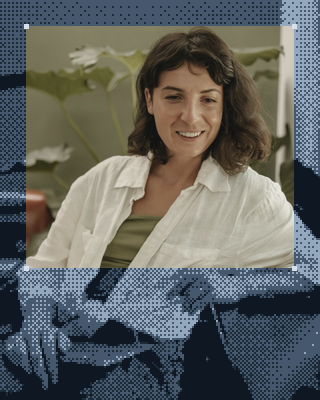 A woman smiles, sitting at a table at home.