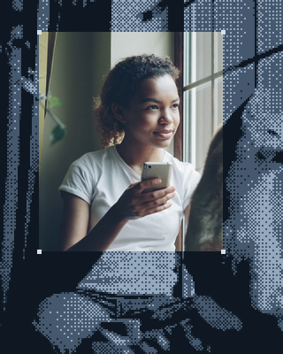 A young woman looks out the window, phone in hand.